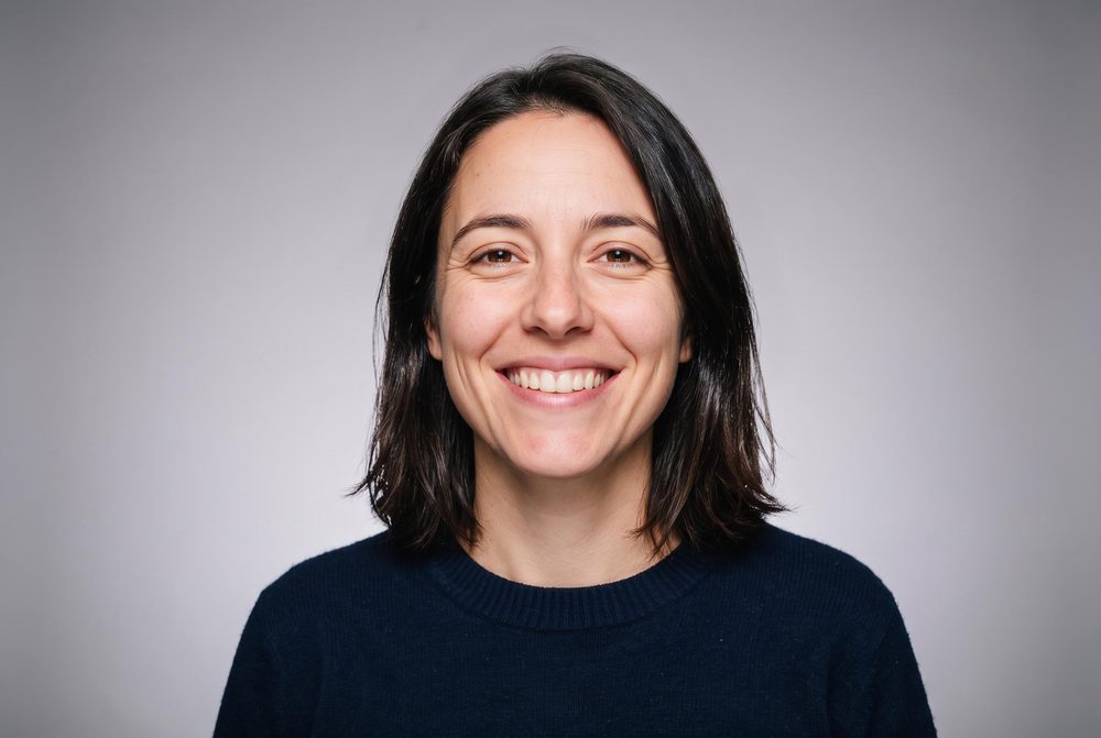 Same headshot on a soft studio grey background